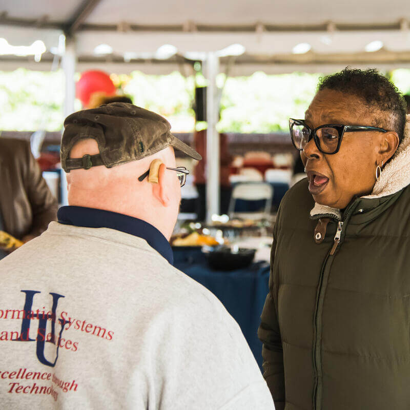 Howard staff enjoying a conversation at a catered celebration.
